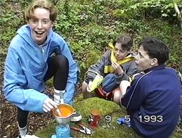 Tom stirs his soup with an improvised "stirring rod" watched by Eliot & Gavin 